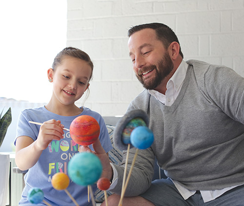 dad and daughter painting the planets